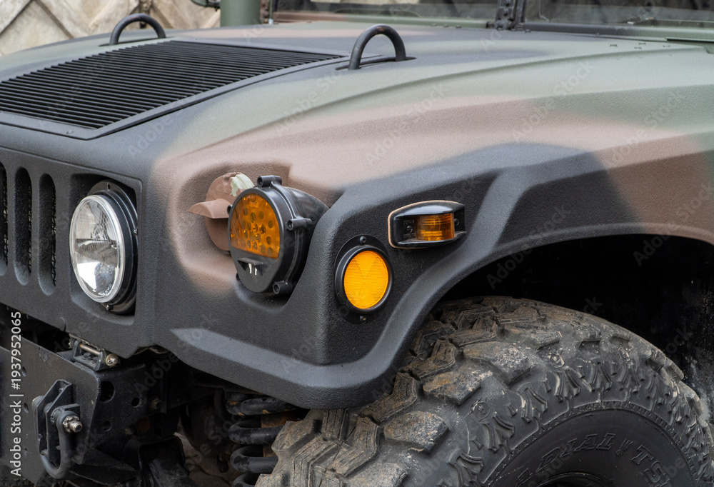 Fototapeta premium Military Humvee parked on an street, showcasing its rugged design and operational readiness in a secure military base. Khaki camouflage military Hummer front view. HMMWV.