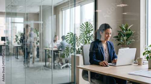 Confident businesswoman working on laptop in modern office space with plants