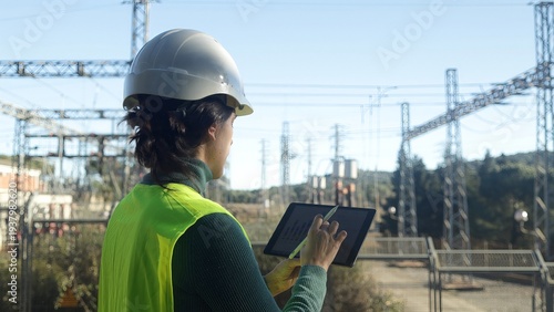 Quadro su tela Female engineer reviewing data on a digital tablet at an electrical power substa