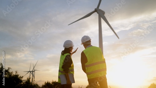 Bild auf Leinwand Engineers discussing wind power generation at a wind farm during sunset, focusin