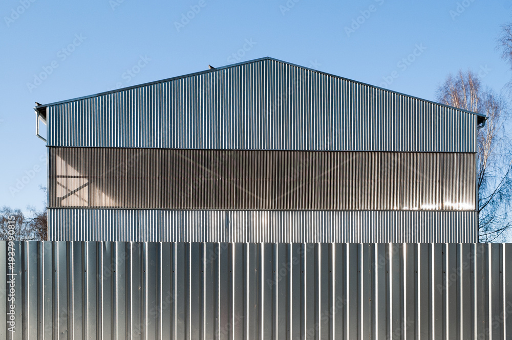 Obraz premium A close-up of a gray metal fence with a metal hangar and blue sky in the background