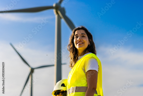 Woman engineer smiling, working at a wind farm, promoting renewable energy