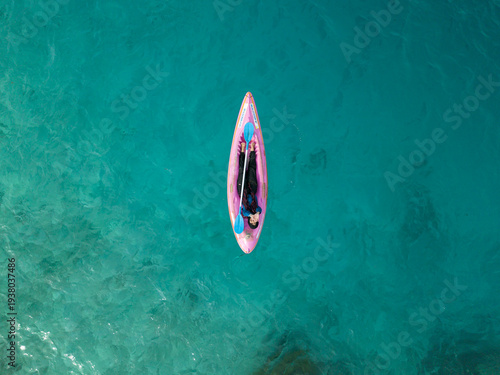 Aerial view of a person on a pink paddleboard drifts silently on the turquoise water, Menjangan Kecil Island, Karimunjawa, Jawa Tengah, Indonesia.