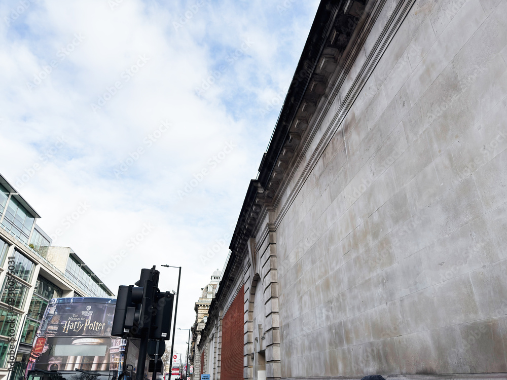 Fototapeta premium London street scene with historic stone wall and Harry Potter bus banner on a storefront