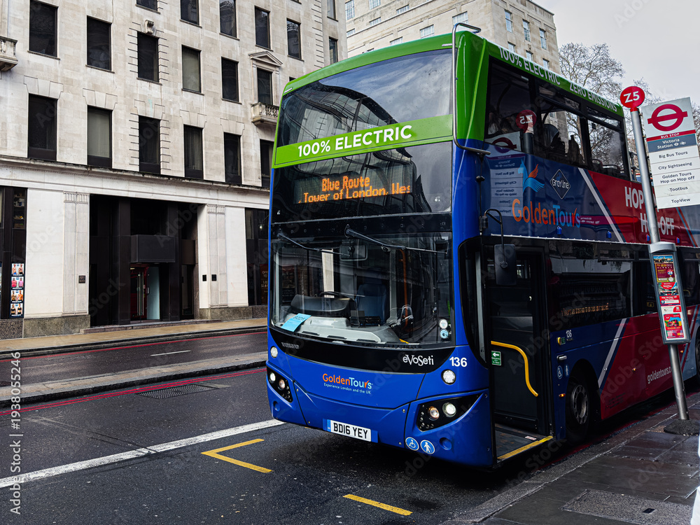 Fototapeta premium London electric double decker Golden Tours bus Blue Route at busy street stop by historic buildings