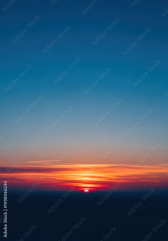 Obraz premium The deep blue sky transitions to soft orange and pink light as the sun disappears below the horizon, bathing the landscape in cool, tranquil tones, morning, celestial, natural