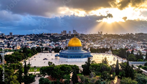 Sun rays peak through clouds over a city with golden dome, green trees, & pale buildings in distance