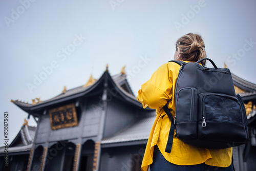 Female traveler wearing yellow jacket in Temples and monuments complex on the Golden Summit of Emeishan mountain, Sichuan, China