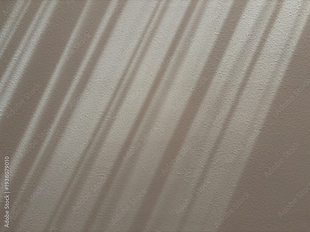 Fototapeta premium Soft window light shadow on a textured wall creating a minimalist abstract background with natural sunlight.