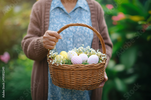 Senior Woman Holding Wicker Easter Basket with Pink and Yellow Decorated Eggs Outdoors