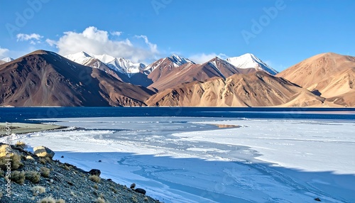 Stunning view of icy lake with mountain range backdrop against a clear blue sky