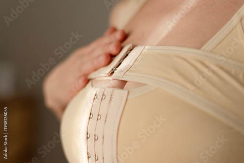 A woman holds the top of her postoperative compression bra, emphasizing beauty after breast reconstruction. Confidence in recovery.