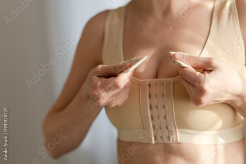 Foto A woman adjusts the straps of her postoperative compression bra