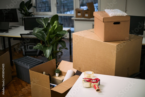Quadro su tela Stacked cardboard boxes and cleaning supplies occupying modern office workspace,