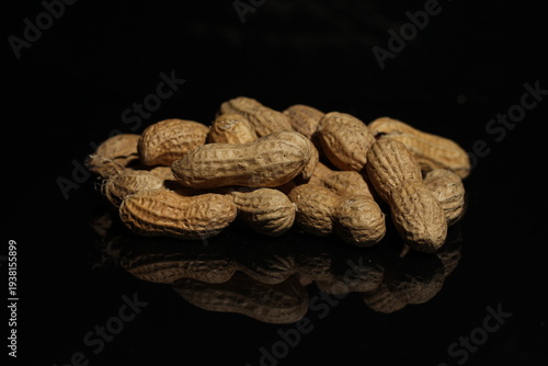 Tableau sur toile Isolated pile / heap / mound of in shell peanuts against a black background with