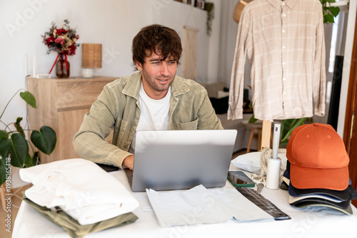 Konstfotografi Man managing online second hand clothing business from home, using laptop for e-