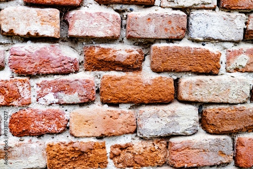 Vintage weathered red brick wall with cracked peeling plaster texture