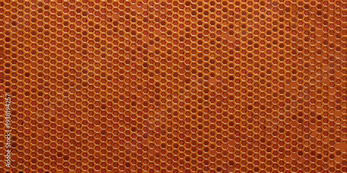 Close up of an orange metal surface with a hexagonal hole pattern