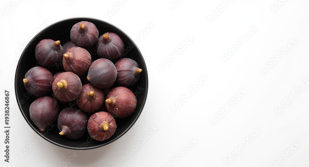 Obraz premium Cluster of fresh purple figs in a sleek black bowl with a neutral white backdrop