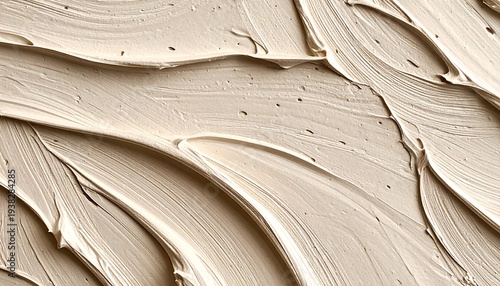 Beige cream spread with curving brushstrokes, smooth texture and delicate shadows filling frame