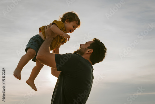new Father's Day Father lifting child against sky