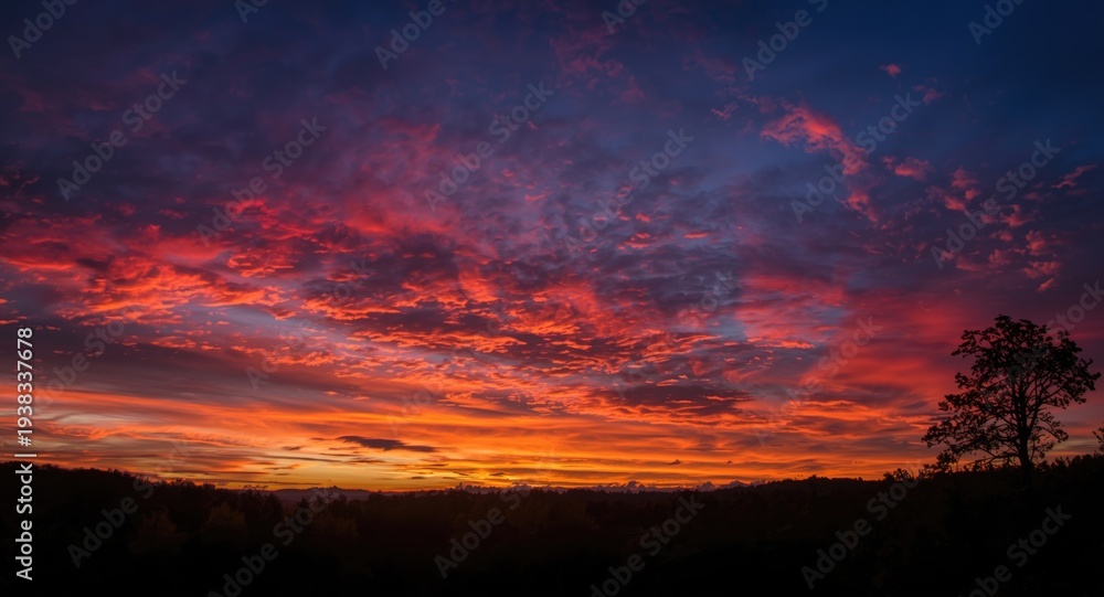 Fototapeta premium Dramatic sunset clouds glowing with vibrant colors in the evening sky over peaceful nature