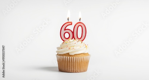 Celebratory cupcake featuring a flickering number 60 candle with an unadorned white backdrop
