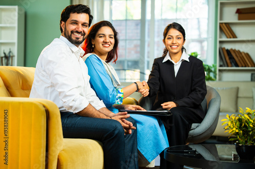 Indian young happy couple signing and shaking hands after discussing their legal documents