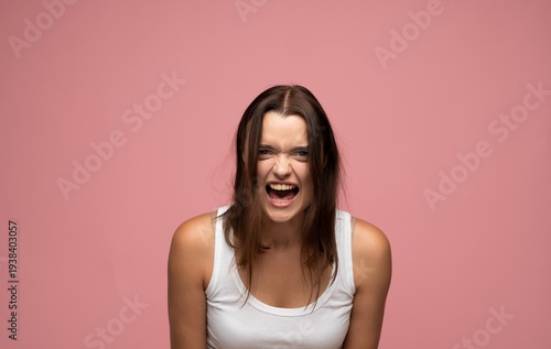 Woman screaming with intense anger and frustration, expressing fury and stress on a pink background
