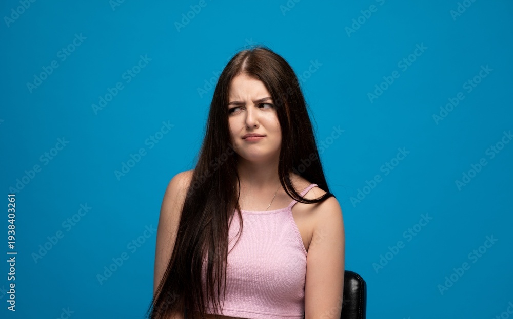 Naklejka premium Young woman expressing disgust, a grimace of dislike and skepticism on her face, disapproval concept