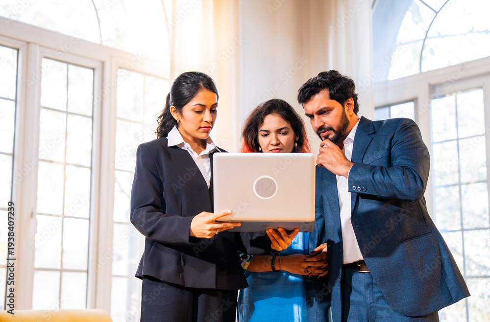 Fototapeta premium Discussing layout, Indian woman real estate agent with young married couple walking in property.