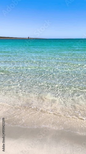 Vertical panoramic view of La Pelosa beach in slow motion showing turquoise water white sand and clear sunny sky