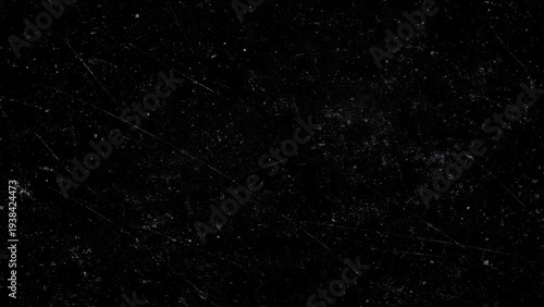 Gritty textured surface with scratches and white specks on a dark background