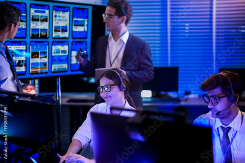 Foto Female IT helpdesk technician wearing headset providing technical customer support during night shift