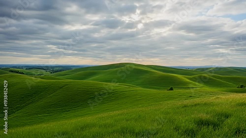 Rolling Green Hills under a Cloudy Sky with Patches of Sunlight