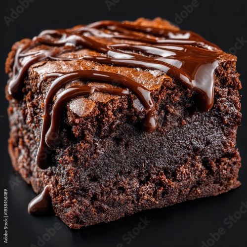 A square, rich chocolate dessert, drizzled with glossy chocolate syrup against a black backdrop