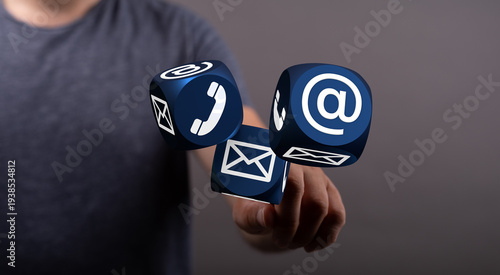 Close up shot of hand touching contact icons on cubes representing communication methods.