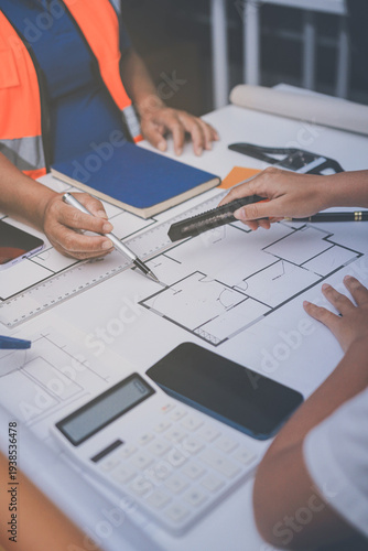 engineer and an architect reviewing blueprints and construction plans together at a bustling construction site