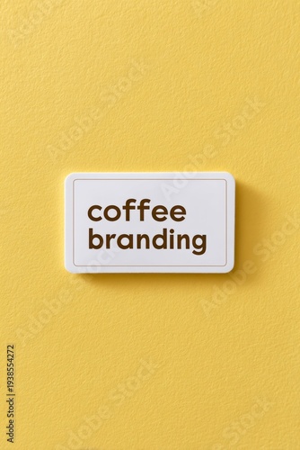 a white rectangular sticker with the text coffee branding on it, against a yellow background