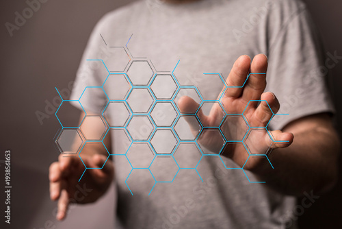 A person interacting with an abstract hexagonal network interface on the screen. The focus is on the technology and data