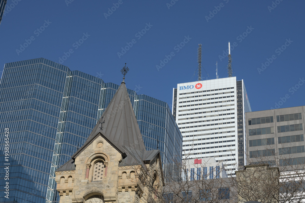 Fototapeta premium contrast of architectural styles and eras: foreground stone tower of St. Andrew’s Presbyterian and office towers in the Financial District (looking east from King and Simcoe), Toronto