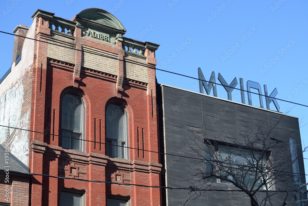 Naklejka premium historic late-Victorian commercial property at 242 Queen St W (originally, a bank) and the rooftop sign of MY Ink Tattoo Piercing & Nail Studio next door, Toronto