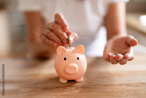 Saving coins in a piggy bank during a budgeting session at home in the morning