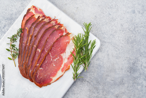 Delicious traditional dried pastrami slices on grey stone background	
