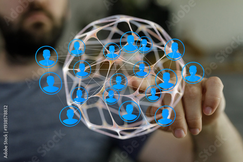 Fotografija Hand holding a digital network globe with connected people icons, representing s
