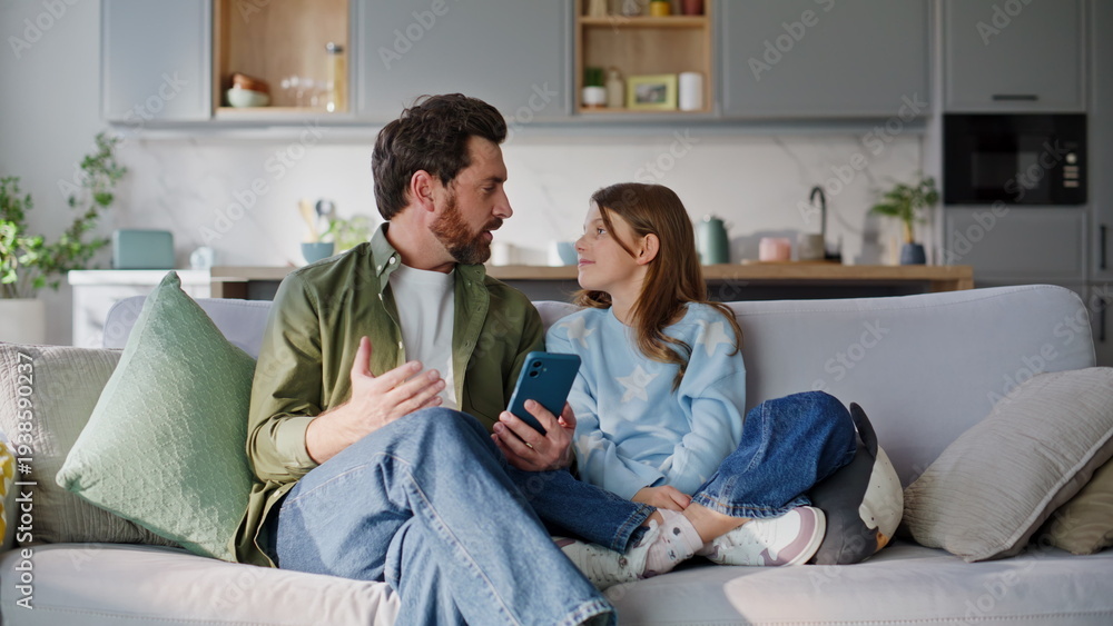 Fototapeta premium Dad kid waving smartphone web camera sitting home couch. Family video call