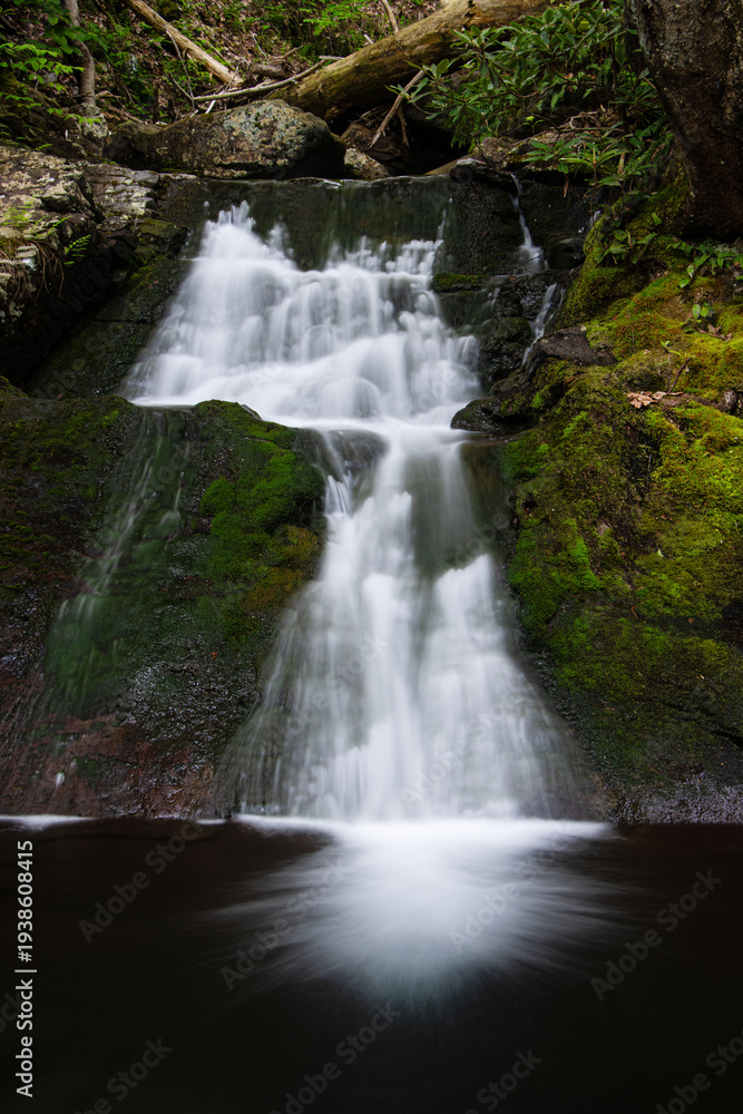 Obraz premium pyramidal flat cascade waterfall flowing water in two drops in mossy rocks in the forest