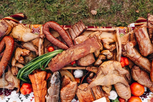 Assorted smoked meats and sausages on a rustic table with smoked fish and vegetables