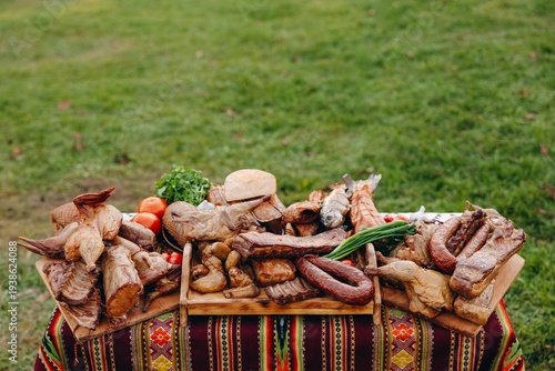 Smoked meats and sausages arranged on a rustic tablecloth for an outdoor barbecue feast