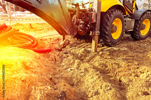 Construction equipment works on a building site, digging into the ground in an urban area during daytime hours